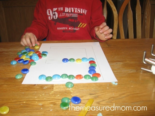 child placing gems into block letter E