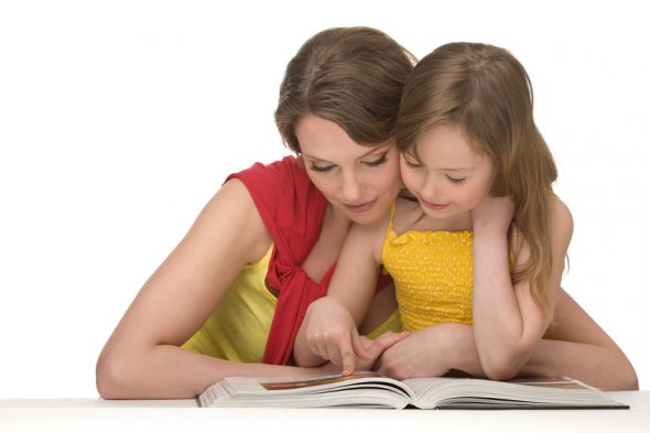 Mum and daughter sit at table and read book